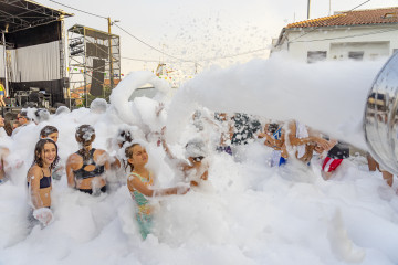 Tłum ludzi bawiący się w jaskrawozielonej, świecącej pianie UV podczas nocnej imprezy klubowej.